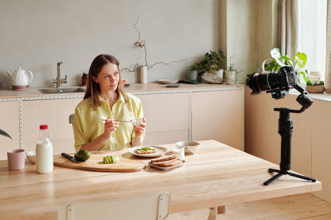 services-04 Woman recording a healthy breakfast vlog in a modern kitchen setting, featuring avocados.