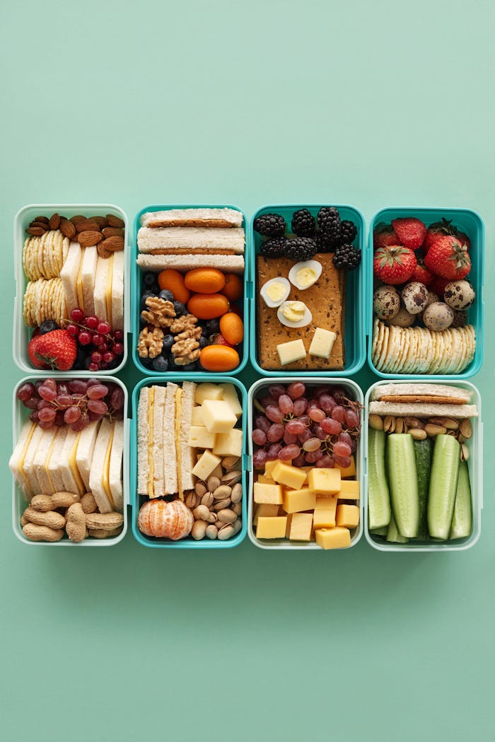 services-03 A top view of assorted snacks in teal containers on a green background.